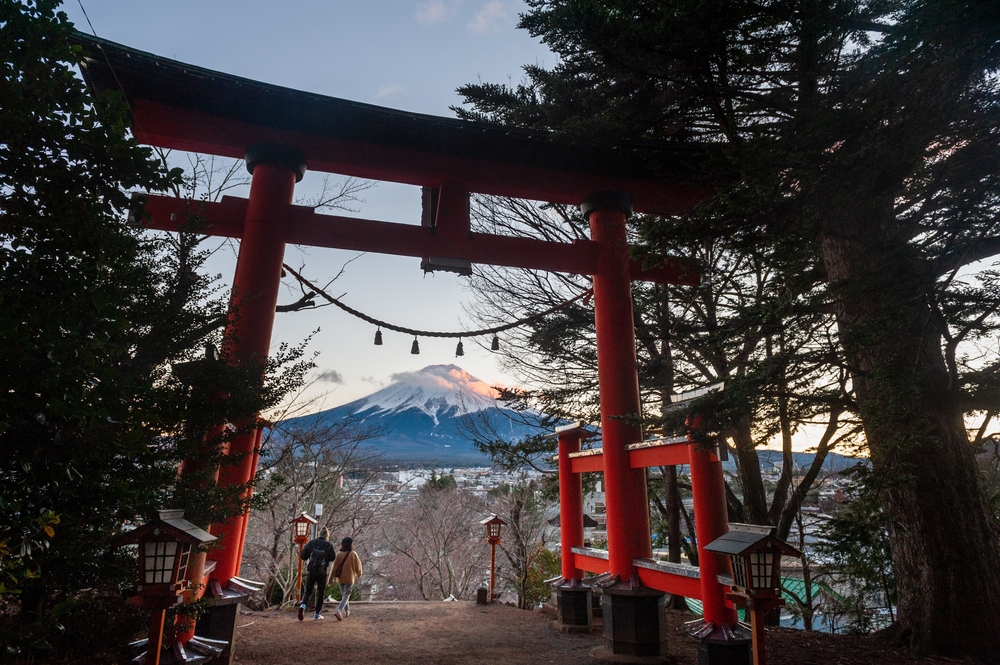 red wooden cross with green trees and mountain in distance
